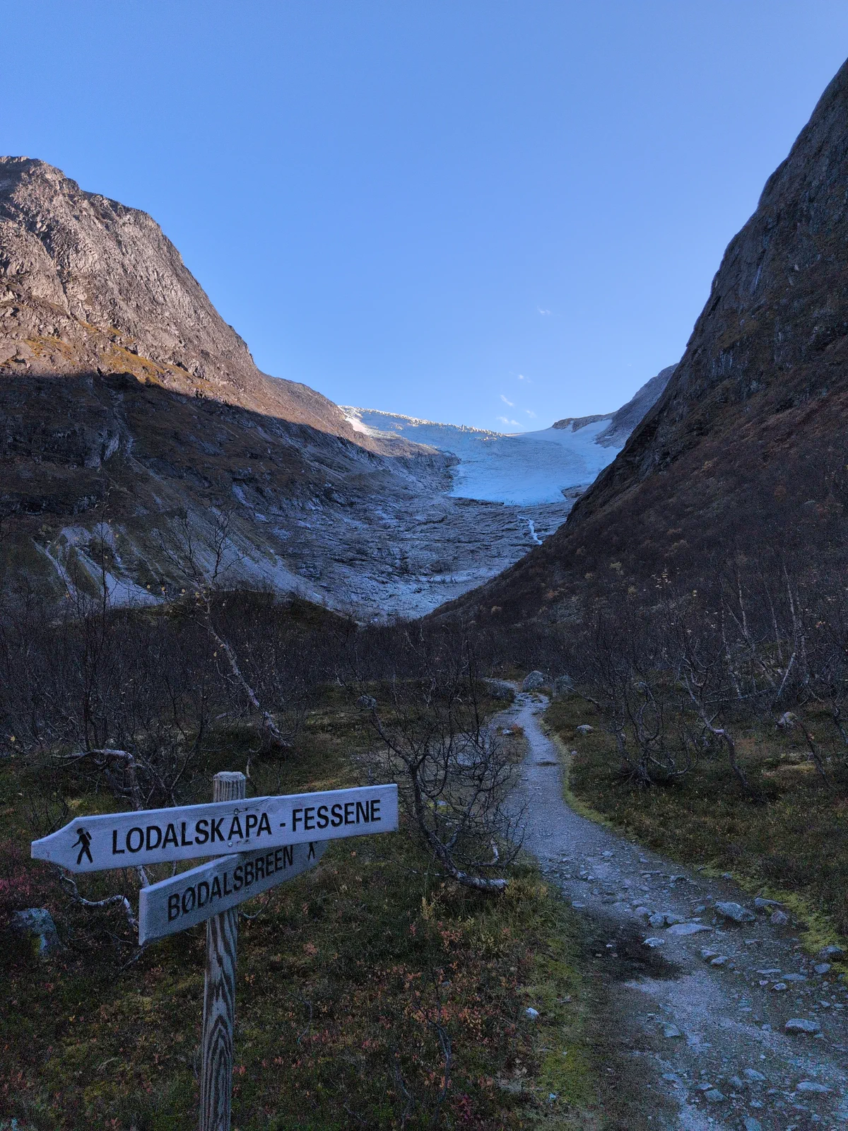 Trail sign with mountains and a glacier in the distance