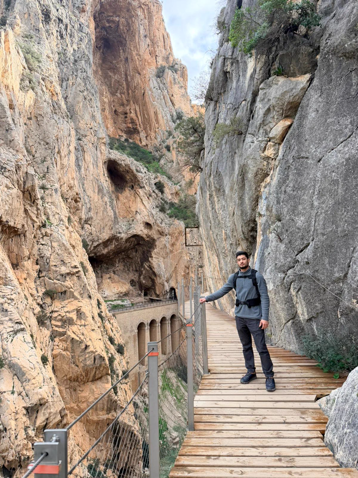 Hiker wearing a helmet on a walkway between the walls of Caminito del Rey