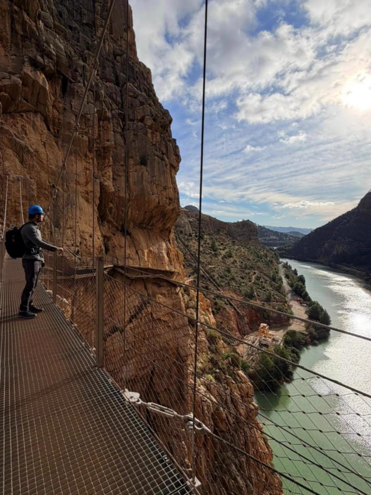 Hiker on a walkway beside the water and valley walls