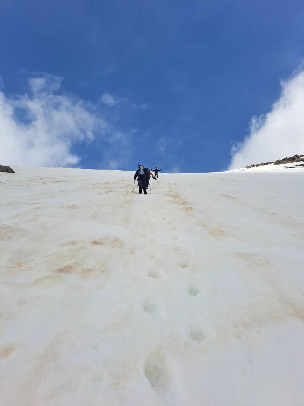 Two mountaineers climb the snow-covered upper slope