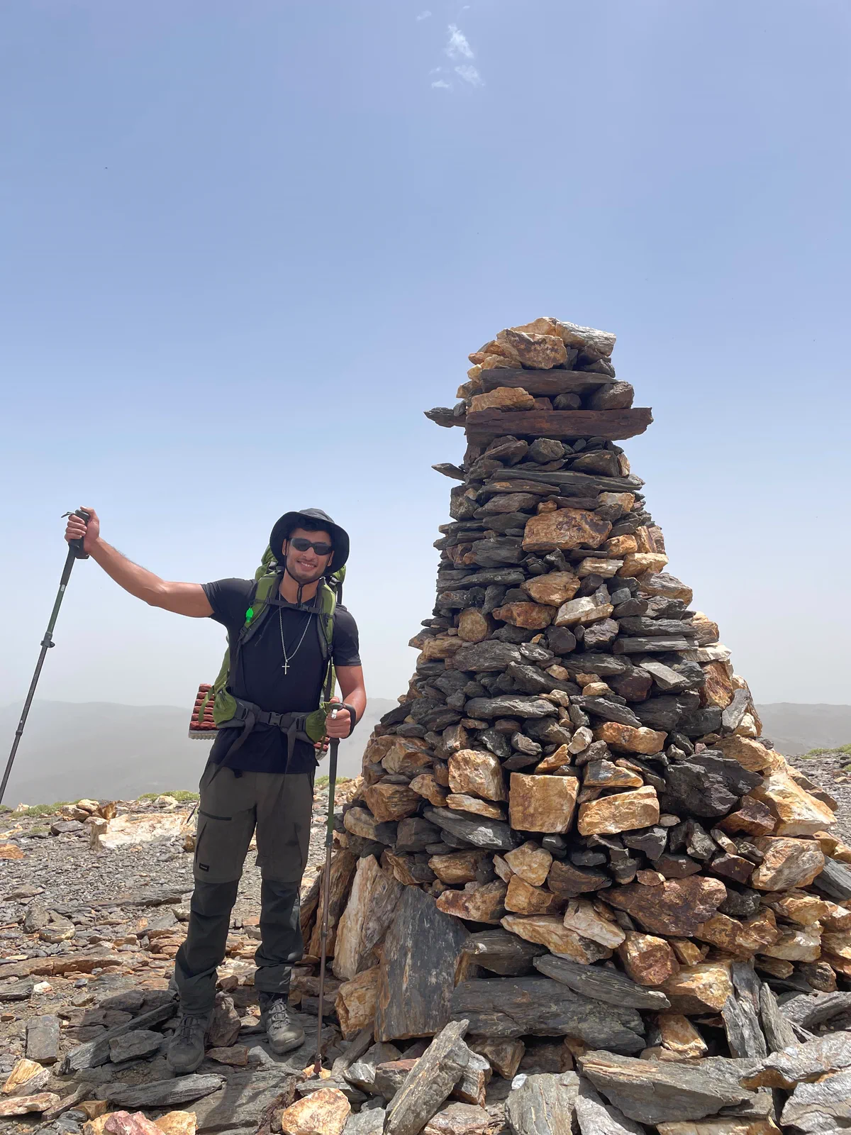 Bauti beside a stone cairn during the traverse