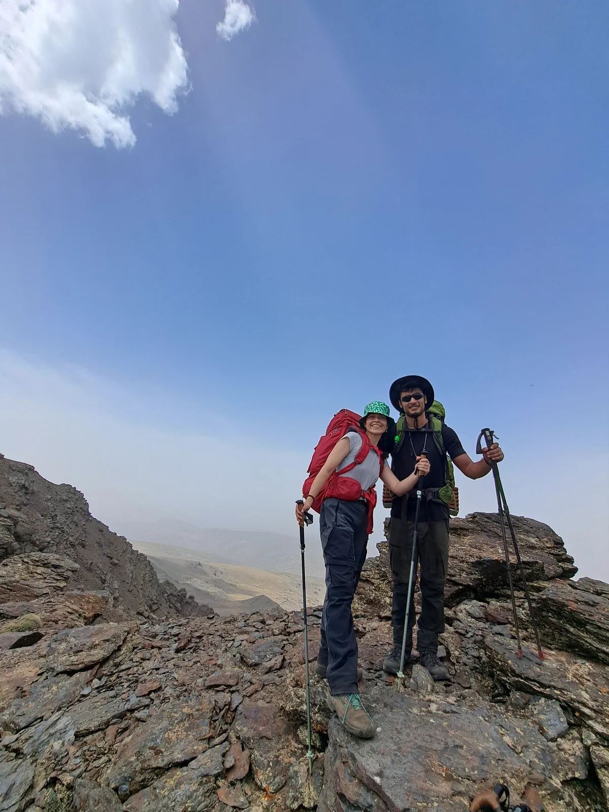 Two group members carrying packs in high-mountain terrain