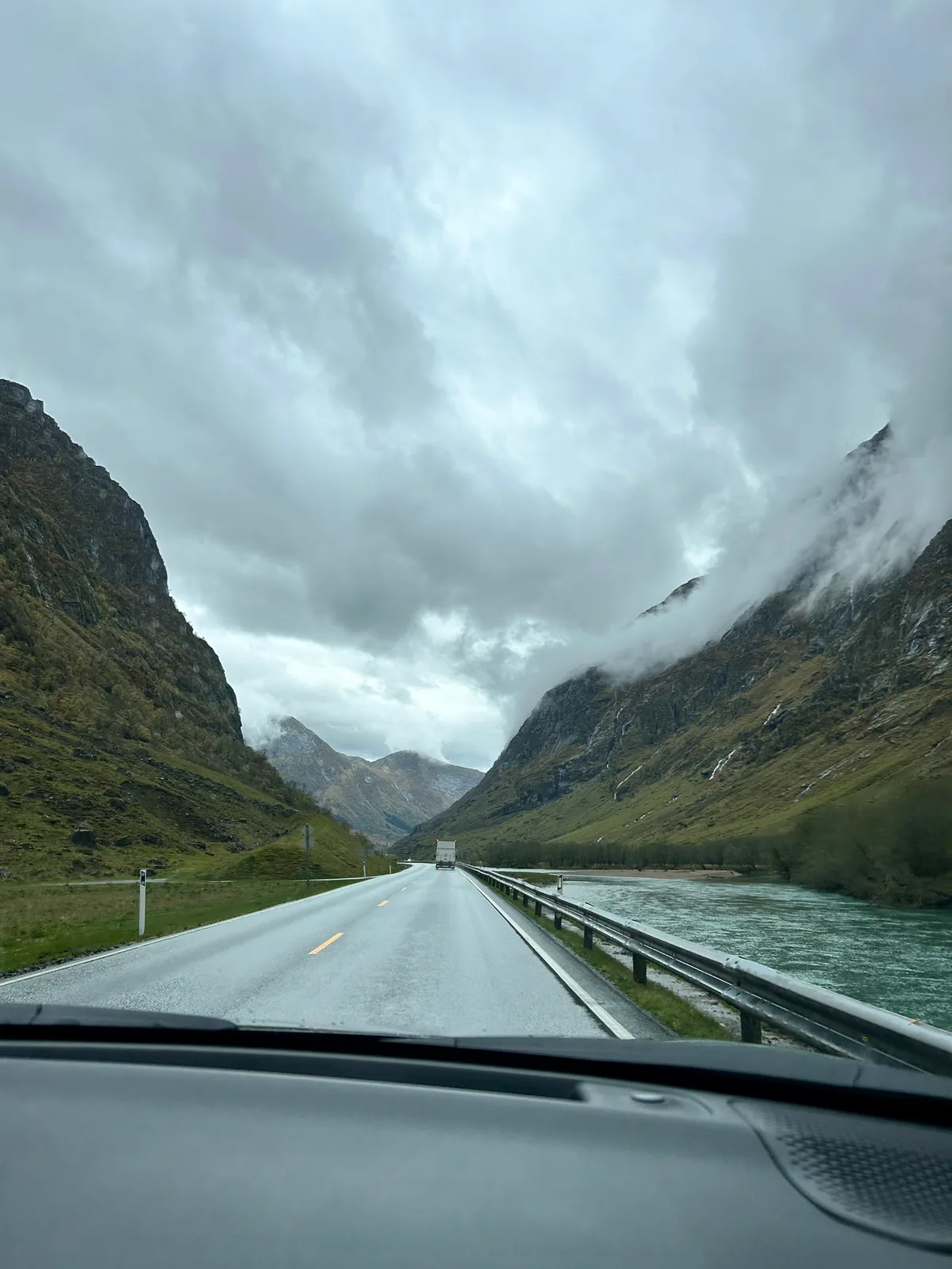 Carretera entre montañas con nubes bajas