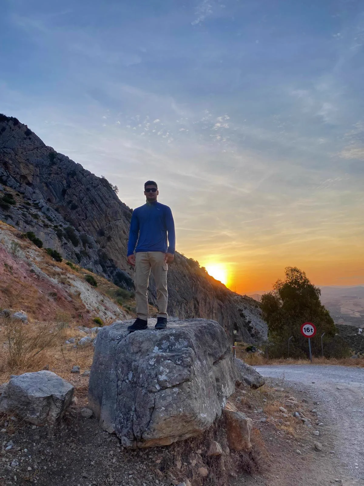 Bauti beside a rock block at the start of the route with the sun low in the sky