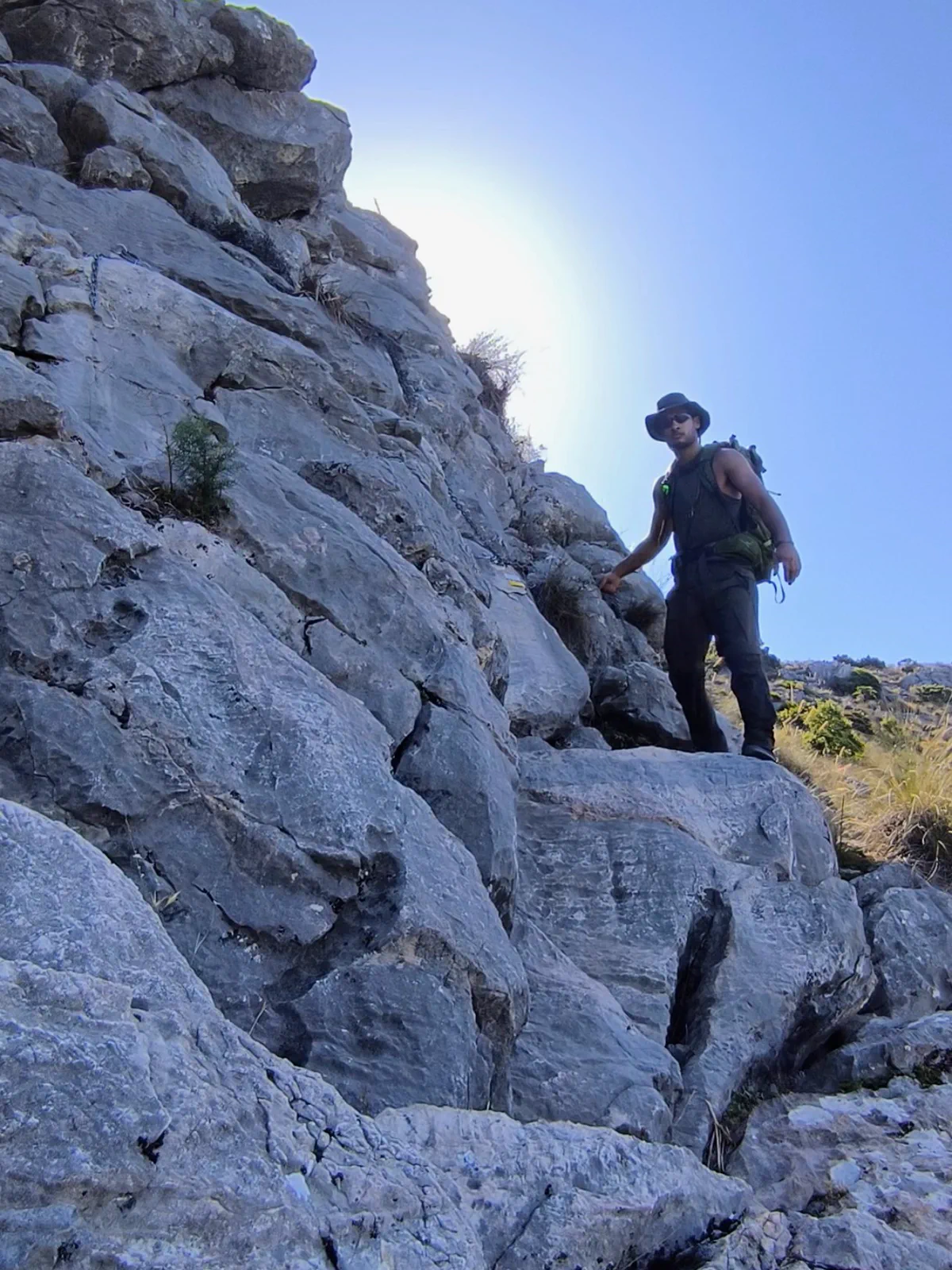 Hiker ascending the limestone terrain of Sierra Blanca towards Pico La Concha