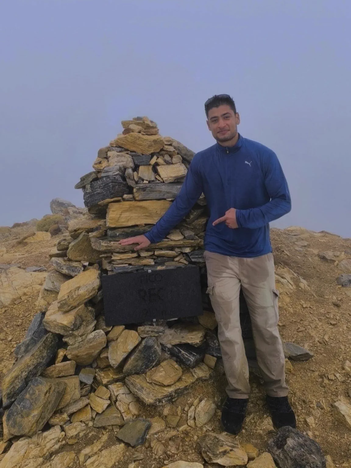Bauti beside the stone cairn on the Pico Torrecilla summit in the mist