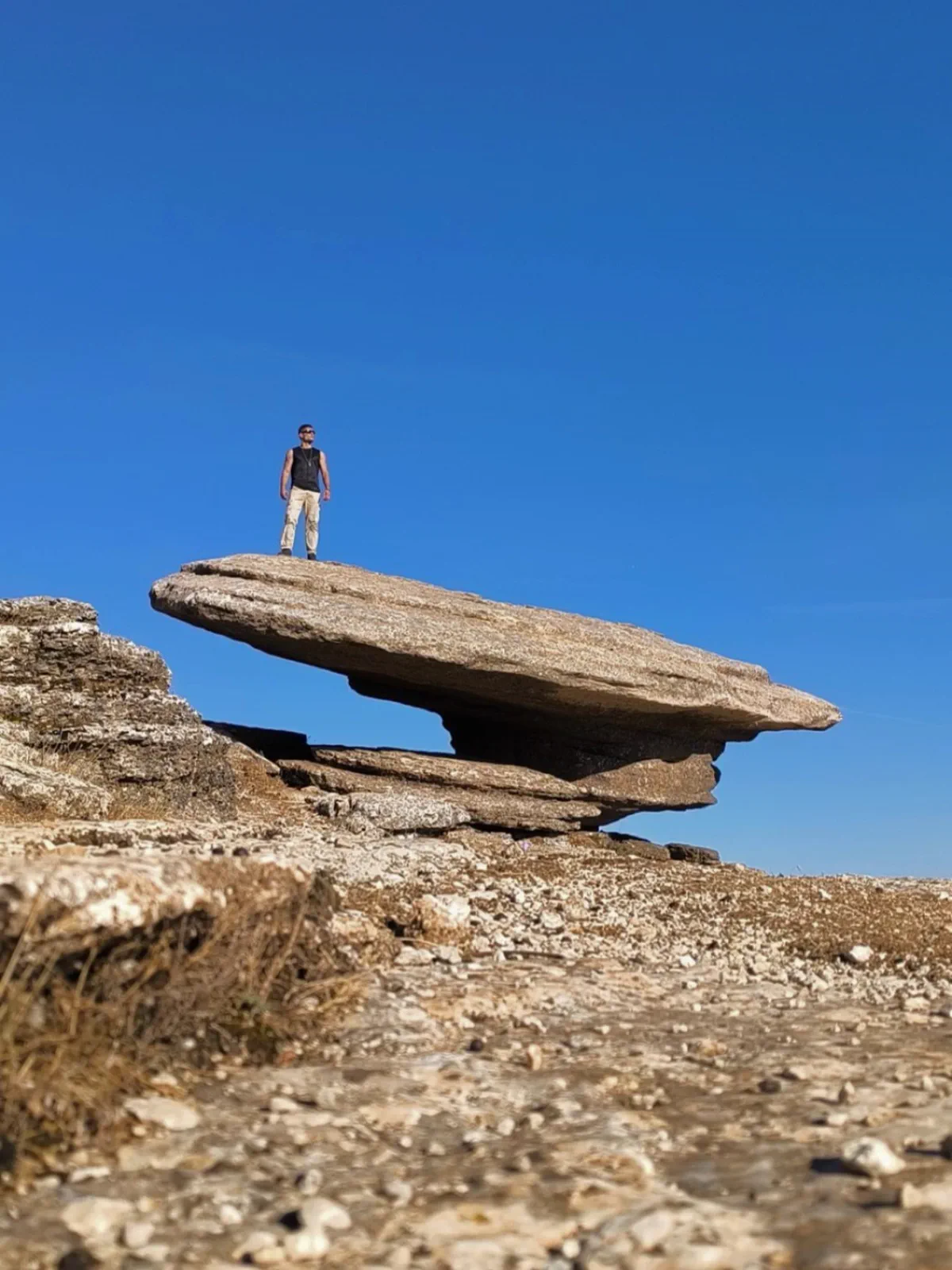 Bauti standing on a huge rock that appears to balance in the Torcal de Antequera